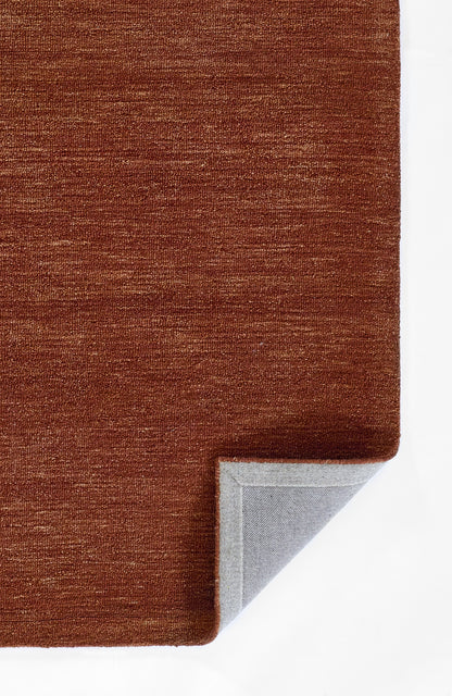 Rust-orange textured rug with woven pile; folded corner reveals light gray underside.