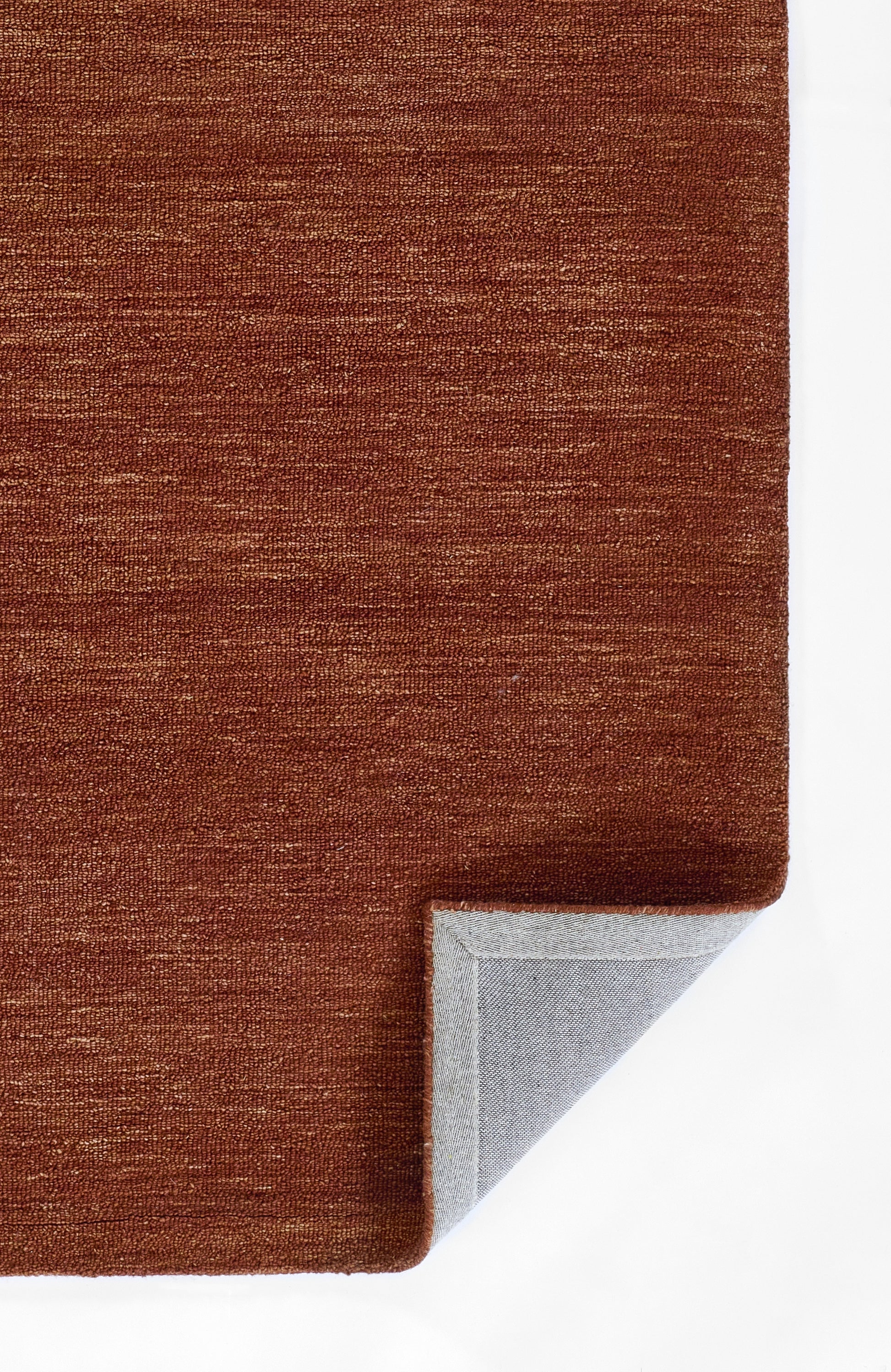 Brown textured rug with subtle heather weave and light gray underside visible at folded corner.