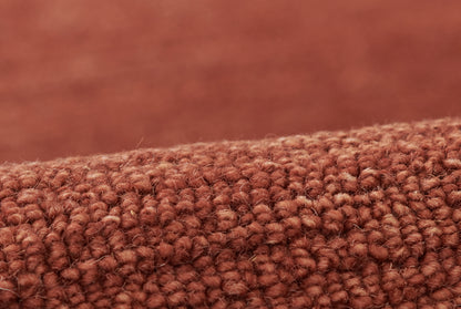 Rust-brown boucle close-up with tight loop pile, cozy rug texture.