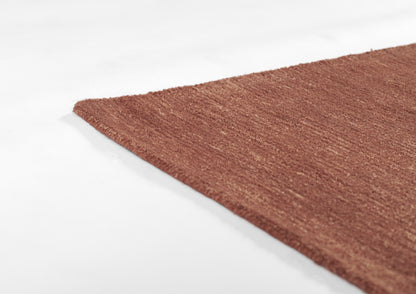 Rust-brown textured fabric rug with visible fibers and a frayed diagonal edge on white background, 5' x 8'.