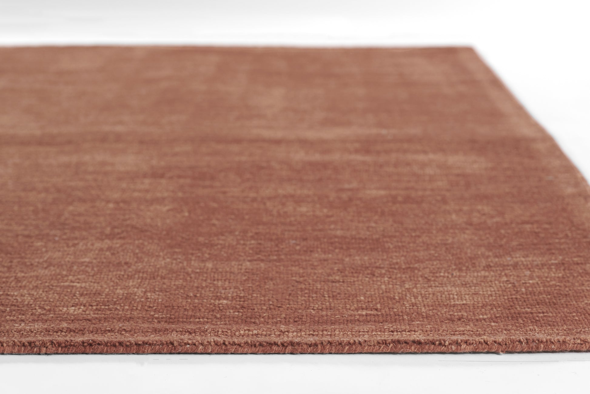 Rectangular rust-brown rug with short pile; soft, woven texture for living room or entryway.