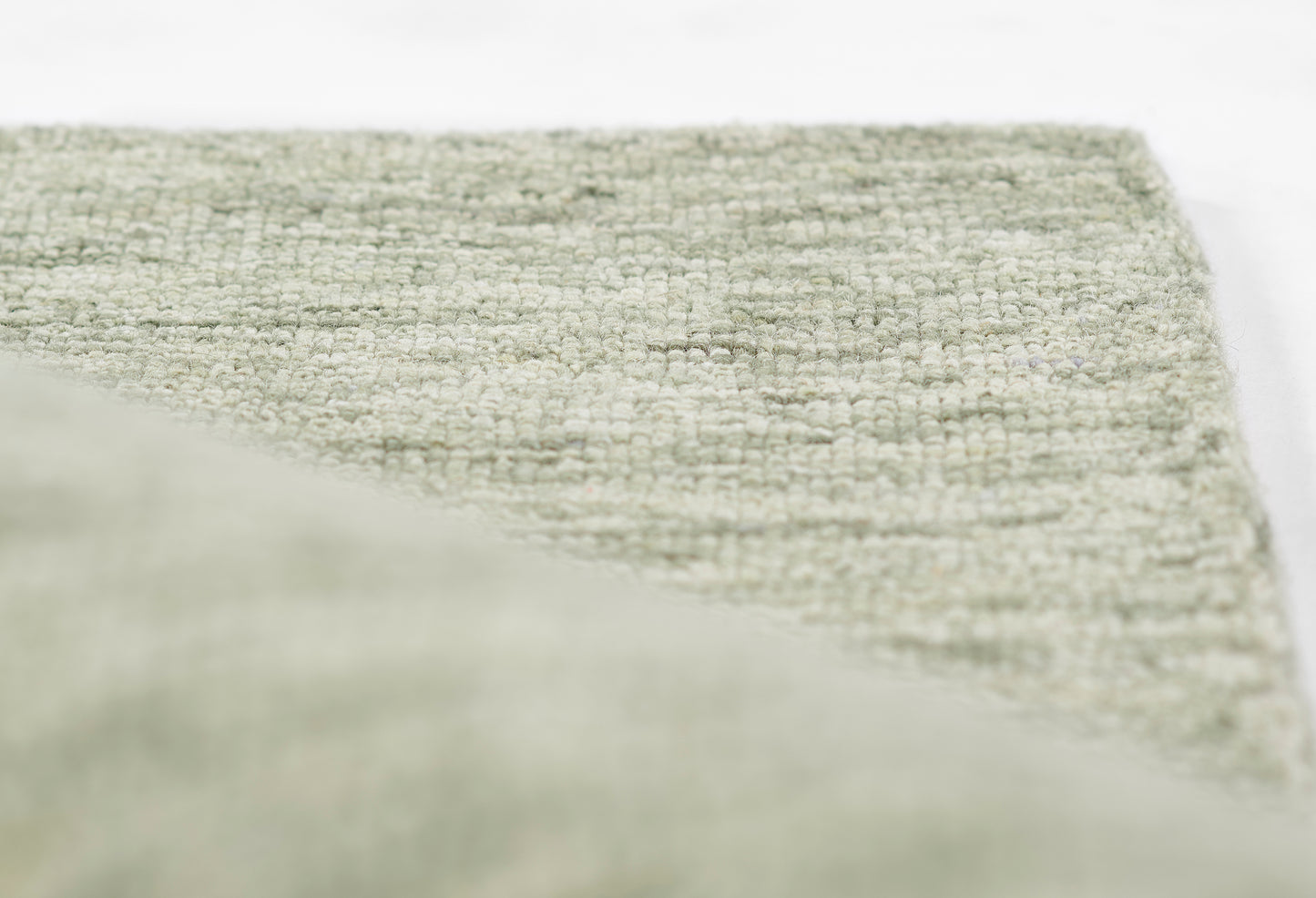 Cream-gray textured boucle rug with dense weave, soft neutral tone and folded corner.