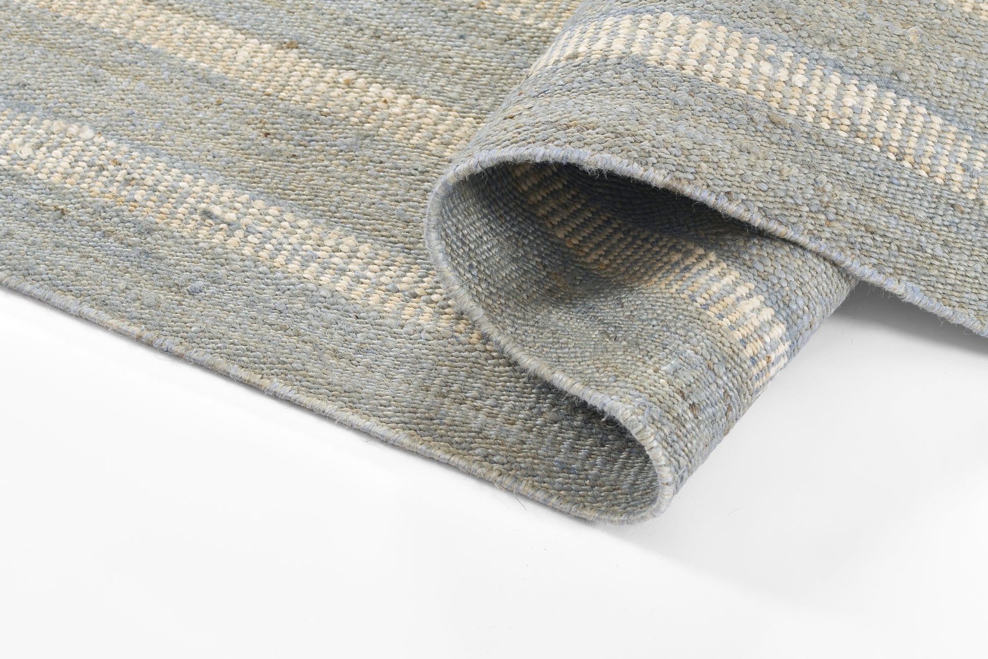 Blue-gray striped woven rug with thick textured weave, rolled edge visible; versatile for living room or bedroom.