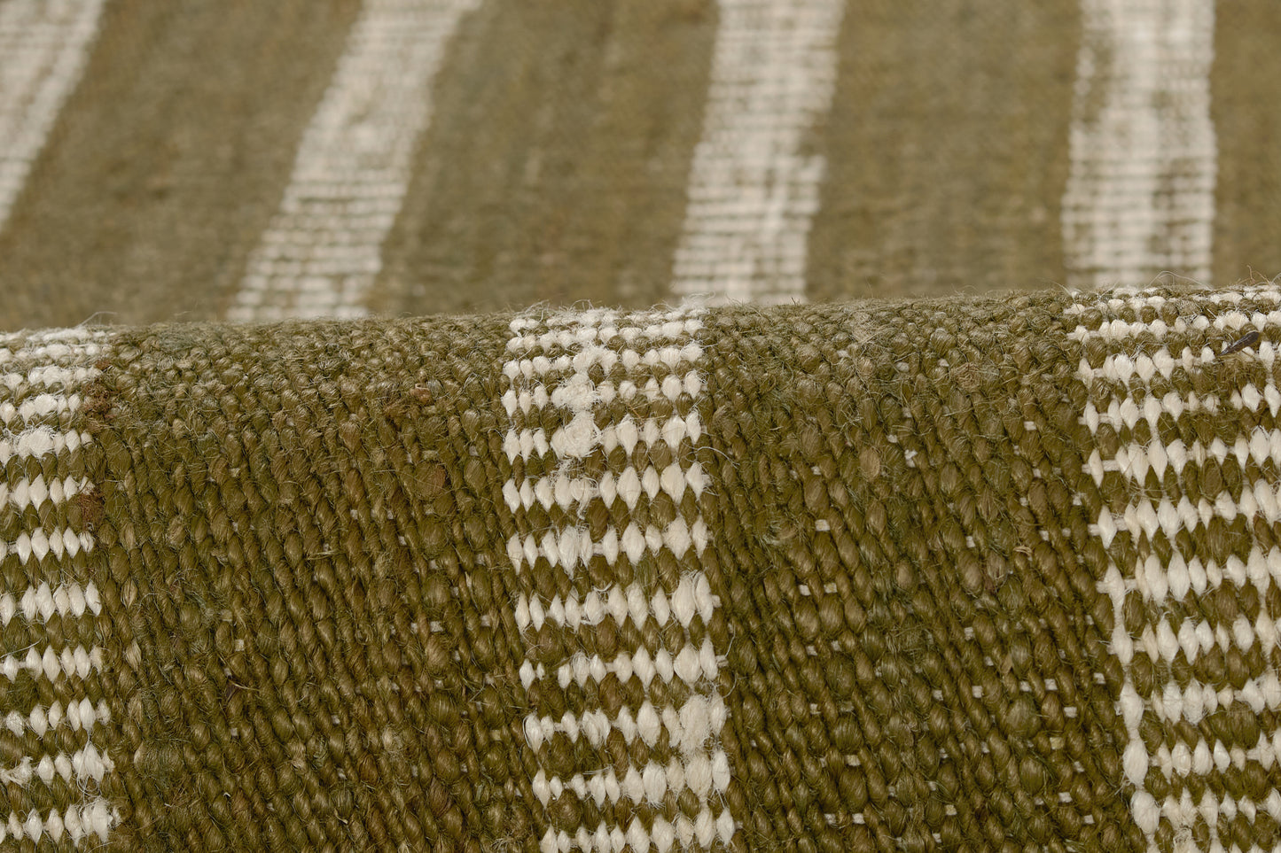 Olive green and white striped woven rug with chunky texture and natural fibers.