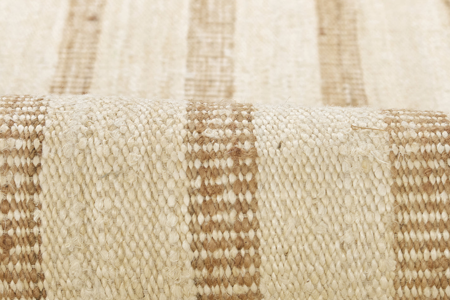 Beige and brown striped woven rug with natural fiber texture; close-up view.
