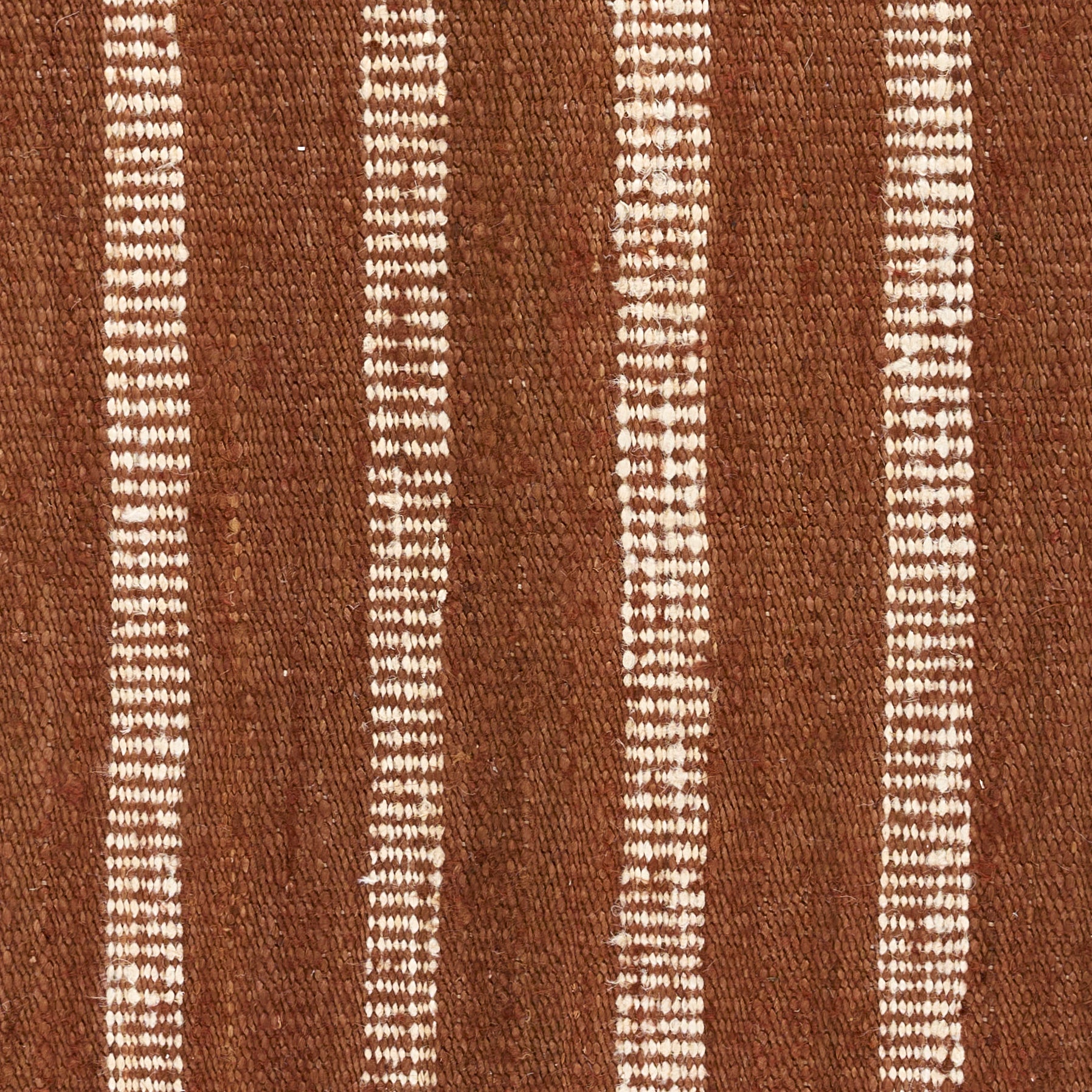 Brown woven rug with vertical white dashed stripes; rustic textured textile.
