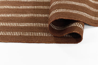 Brown striped woven rug with white thin stripes and folded edge.