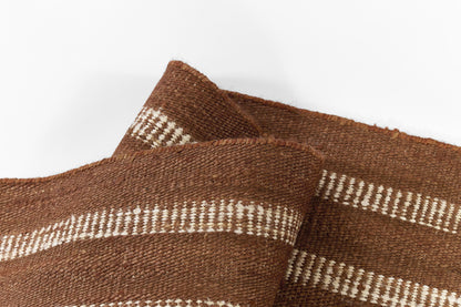 Brown burlap-like woven fabric with white stripes, rough texture folded into a decorative textile.