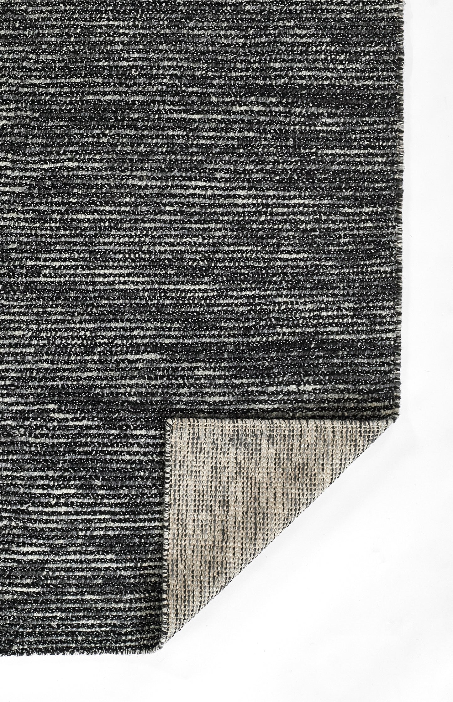 Charcoal gray textured woven rug with speckled finish; folded corner reveals light beige underside.