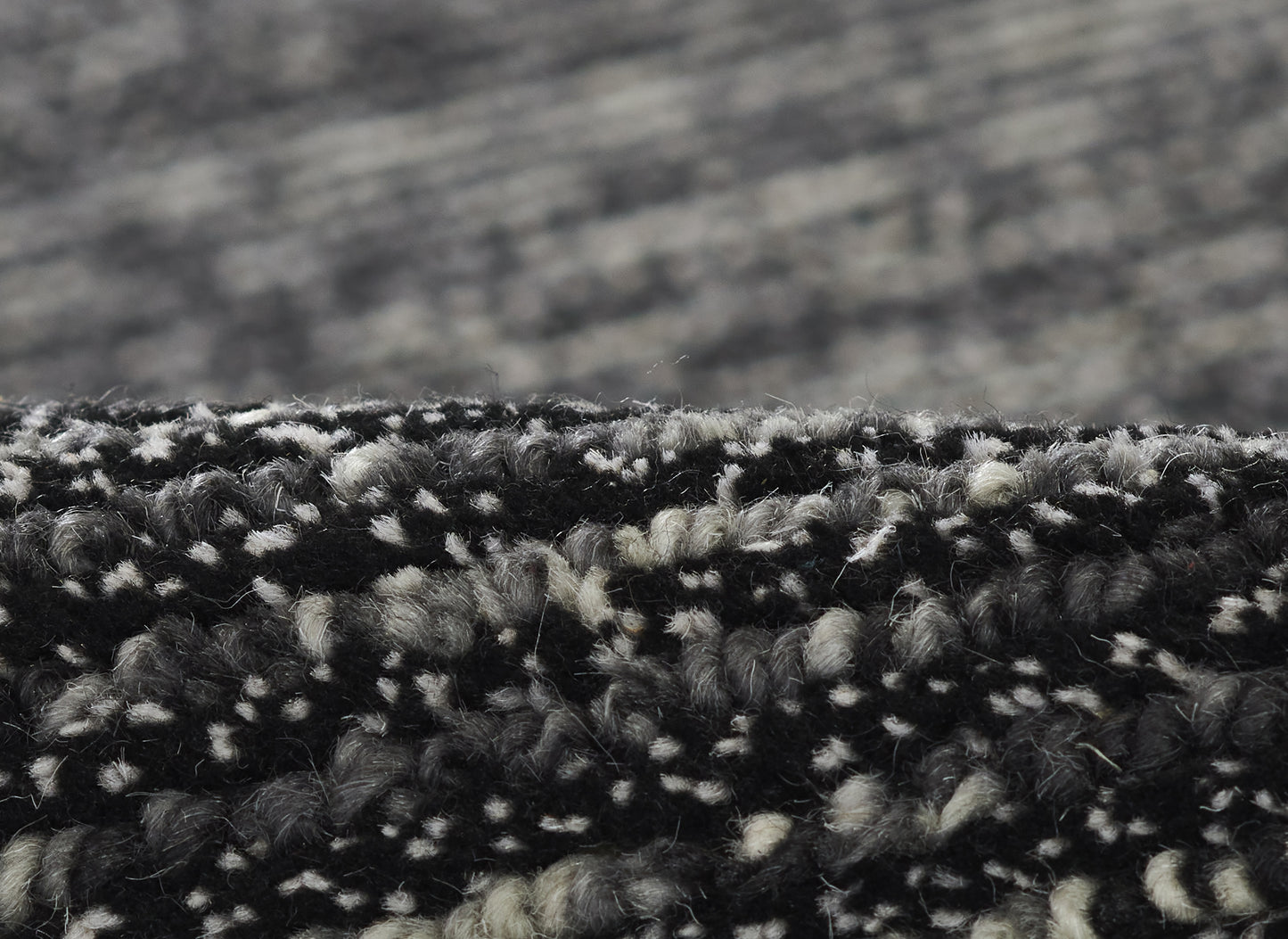 Close-up of black and gray marled loop-pile rug fibers with textured edge.