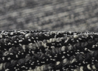 Close-up of black and gray marled loop-pile rug fibers with textured edge.