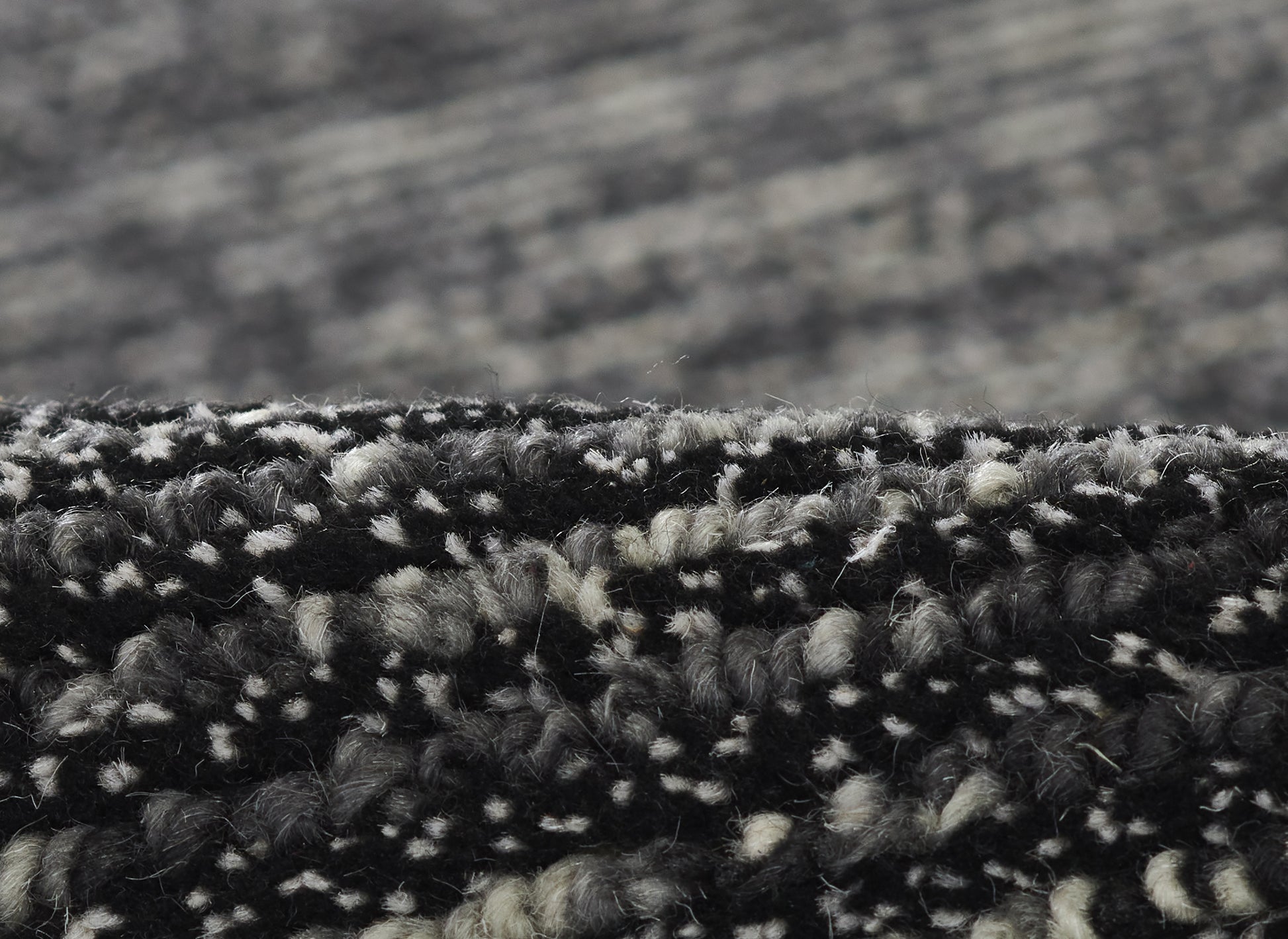 Close-up of a black and gray speckled loop-pile runner rug with dense, textured fibers.