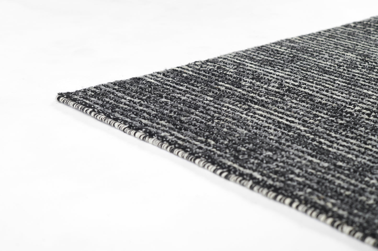 Rectangular dark gray and black woven rug with white specks and light edge binding; low-pile, textured.