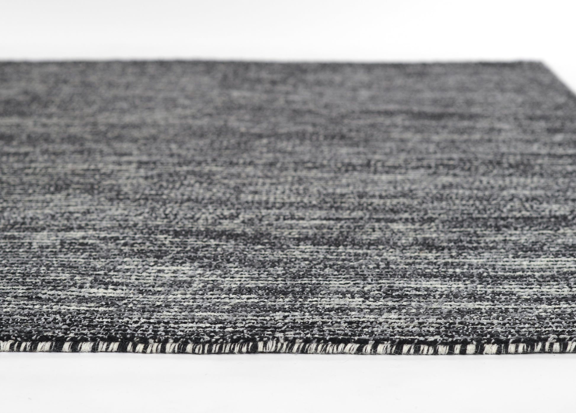 Close-up of a gray marled woven rug with short fringe edge, modern flat-weave style.