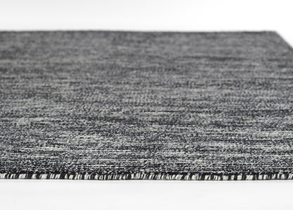Close-up of a gray marled woven rug with short fringe edge, modern flat-weave style.