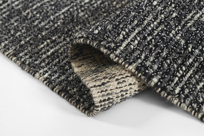 Black and ivory striped woven rug with beige underside, textured looped pile.