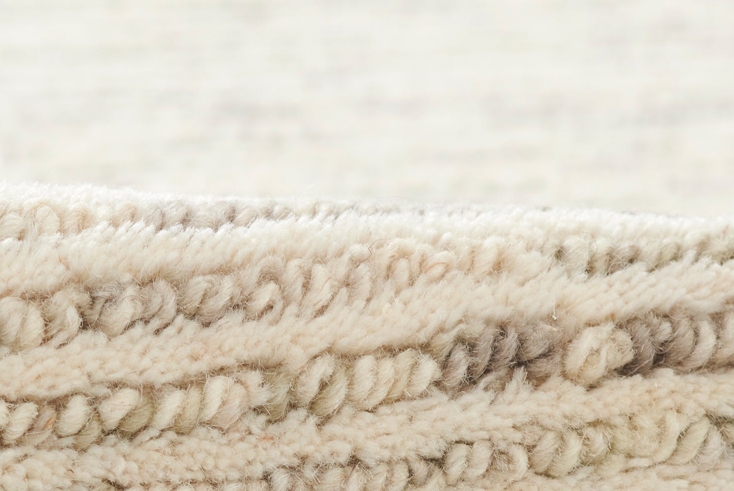 Close-up of cream boucle fabric with thick plush loops and soft beige tones.