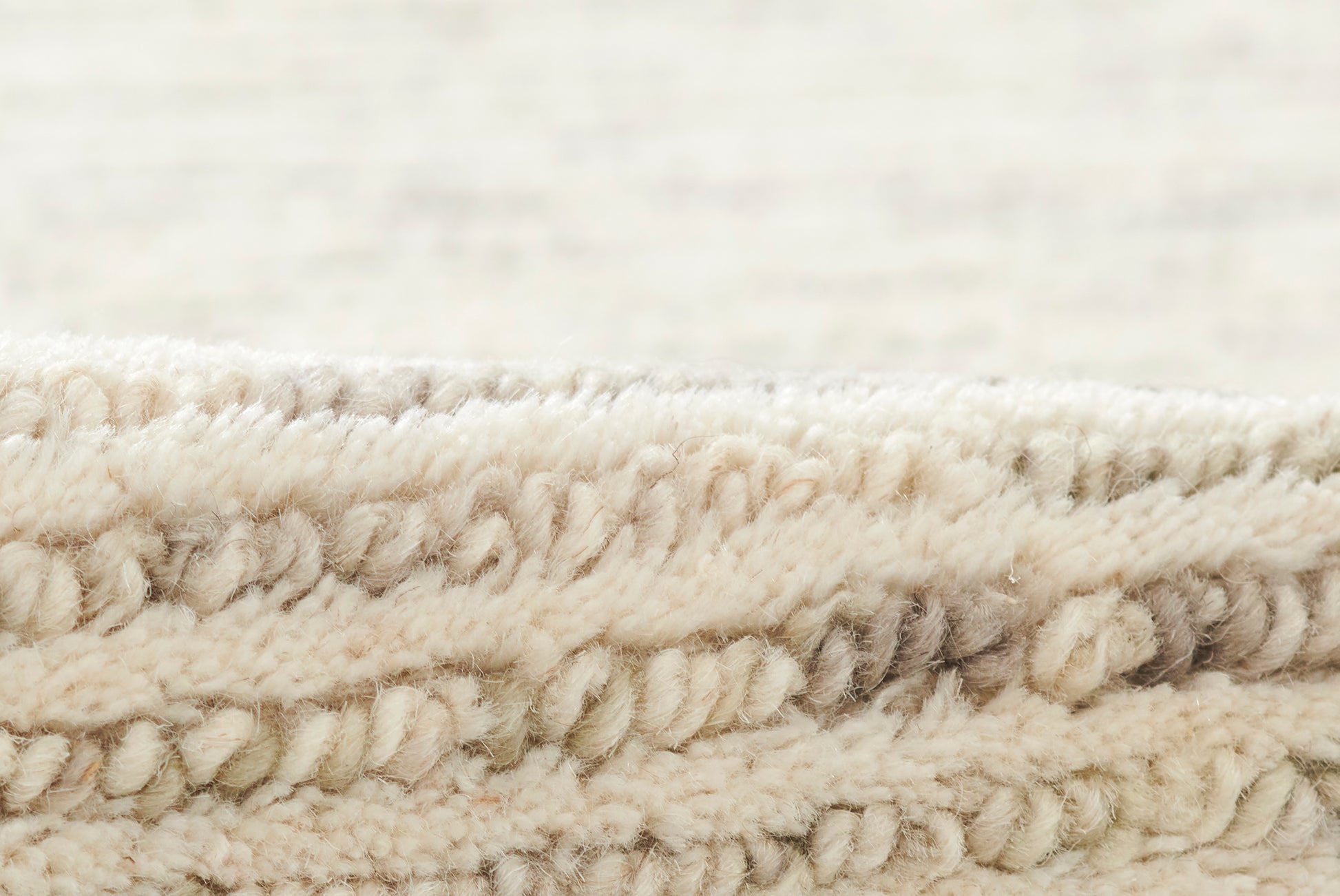 Close-up of cream boucle fabric with thick plush loops and soft beige tones.