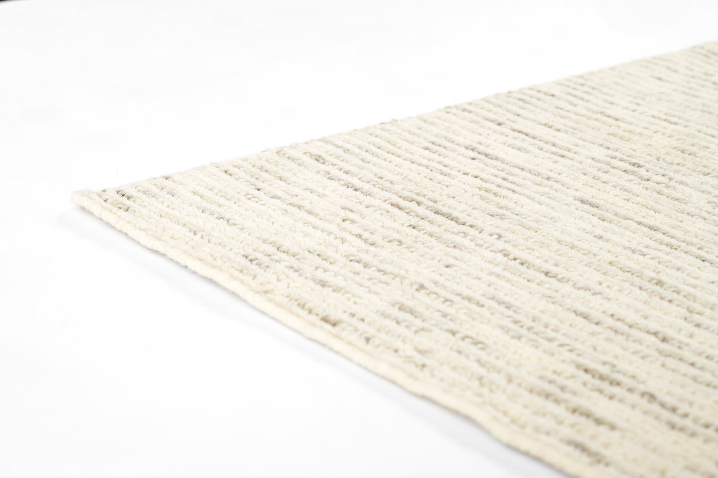 Cream ribbed rug close-up with plush loop pile and curled edge.