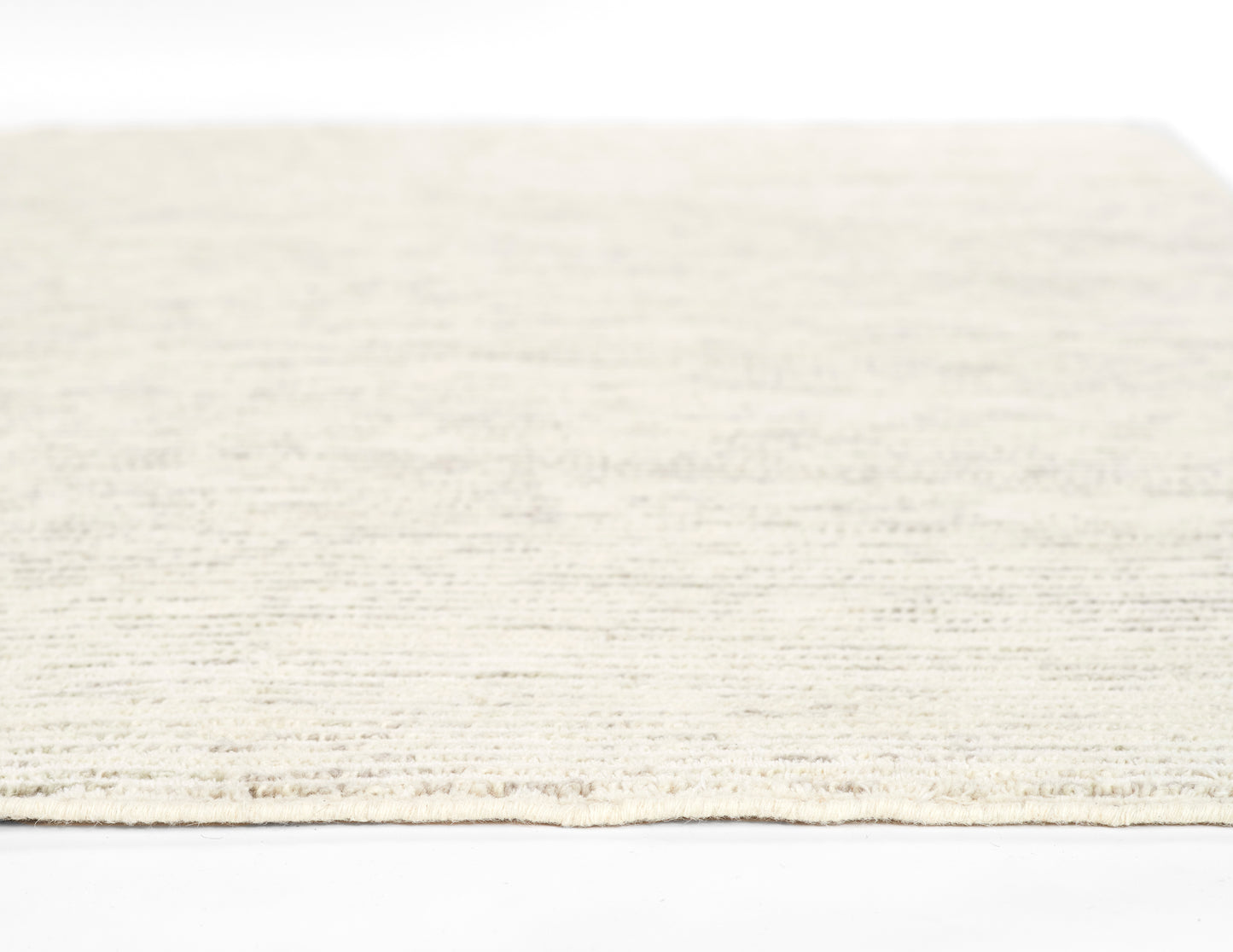 Cream beige textured rug with subtle woven pattern and short fringe along the edge.