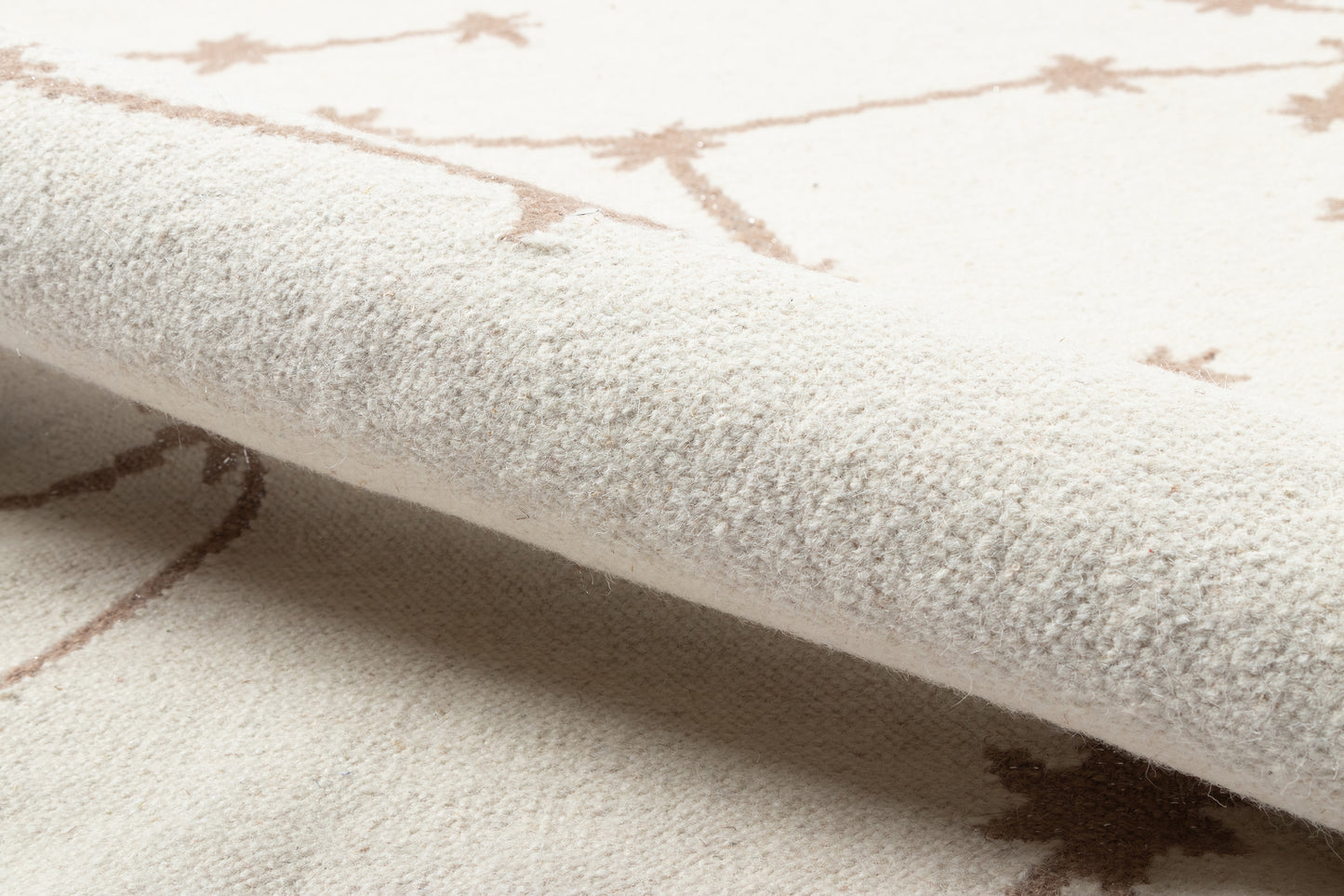 Ivory rug with light brown geometric starburst pattern; soft plush pile and folded edge.
