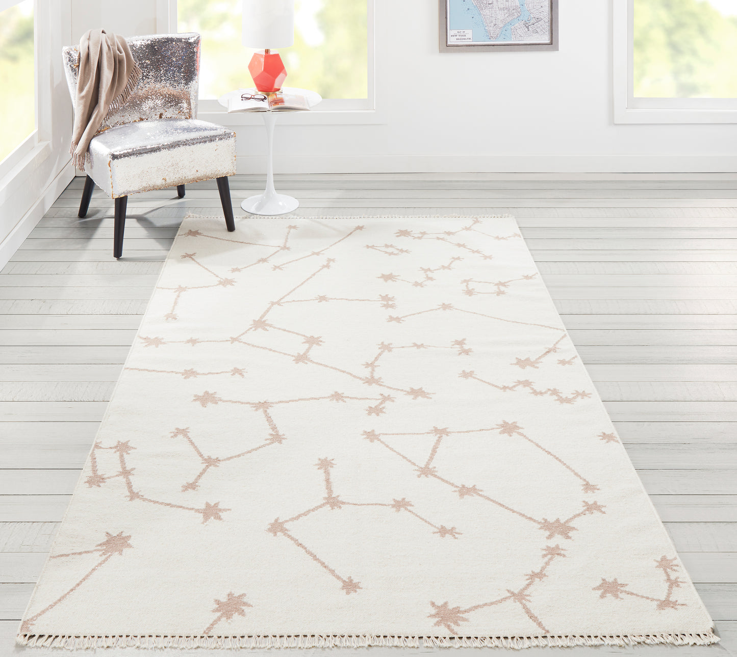 Ivory flat-weave rug with tan branching starburst motif and fringed edges in a bright, modern living room.