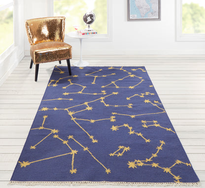 Navy blue rectangular runner 2' x 8' with a gold constellation pattern and fringe, in a bright white room with a gold sequin chair.