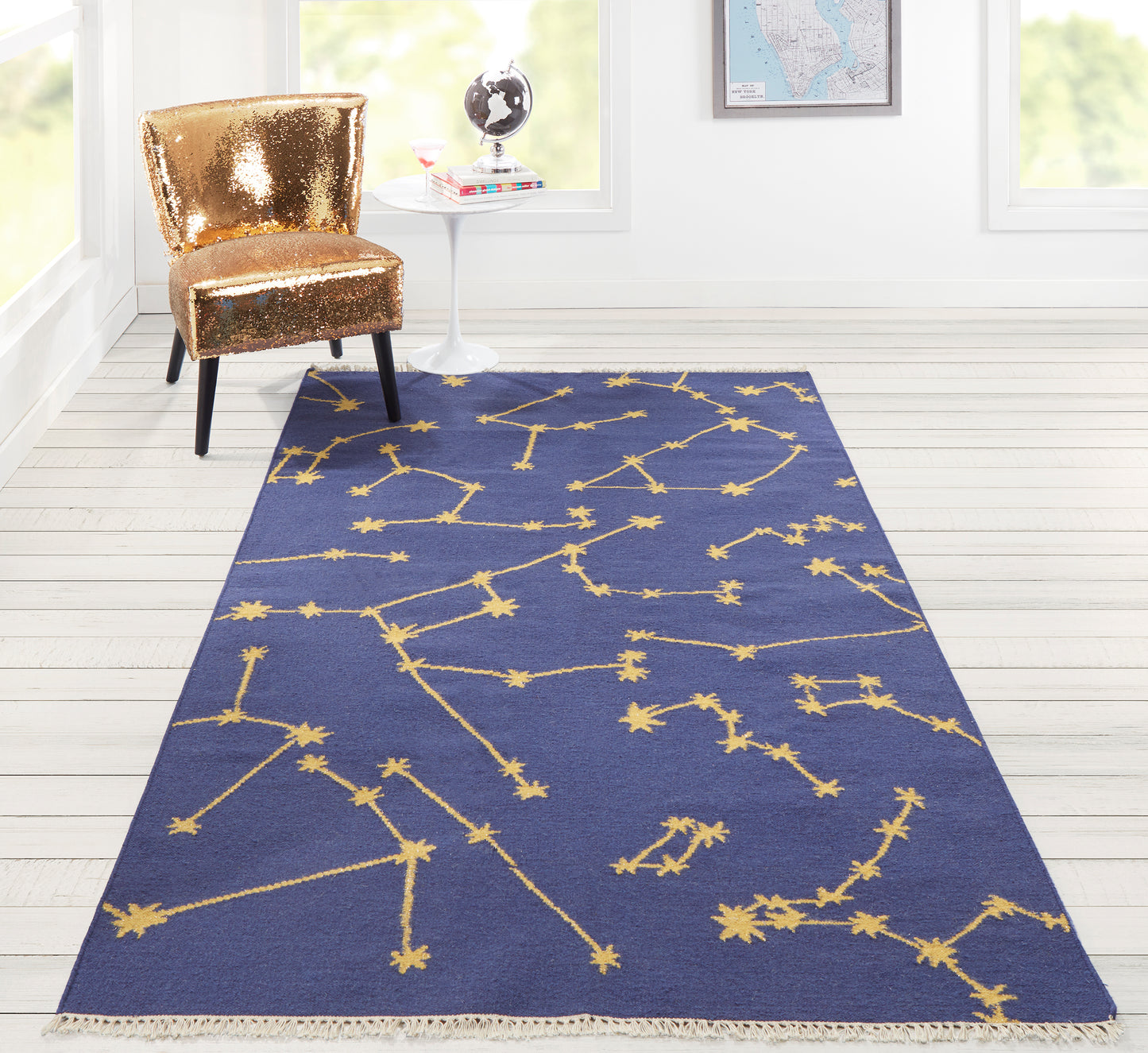 Blue rectangular rug with a gold constellation pattern and fringed edges in a bright modern room.