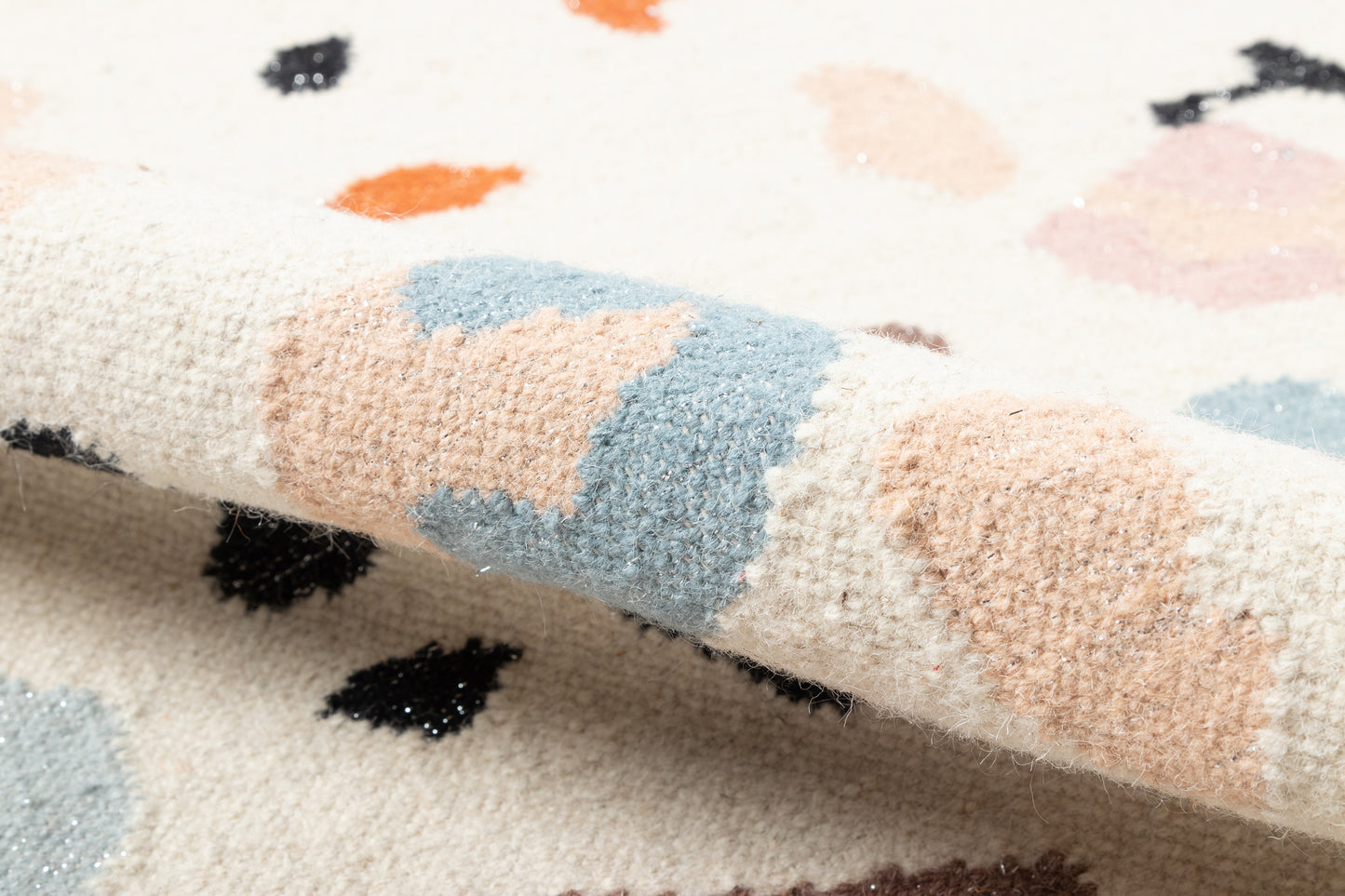 Soft ivory rug with abstract pastel patches in peach, blue, pink and black accents; plush textured pile.