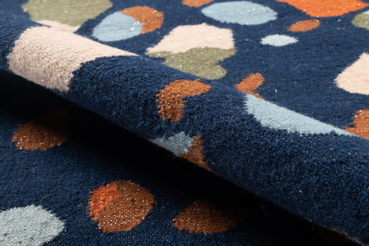 Navy blue rug with abstract multicolor circles in brown, pale blue, beige and olive; soft, high-pile texture.