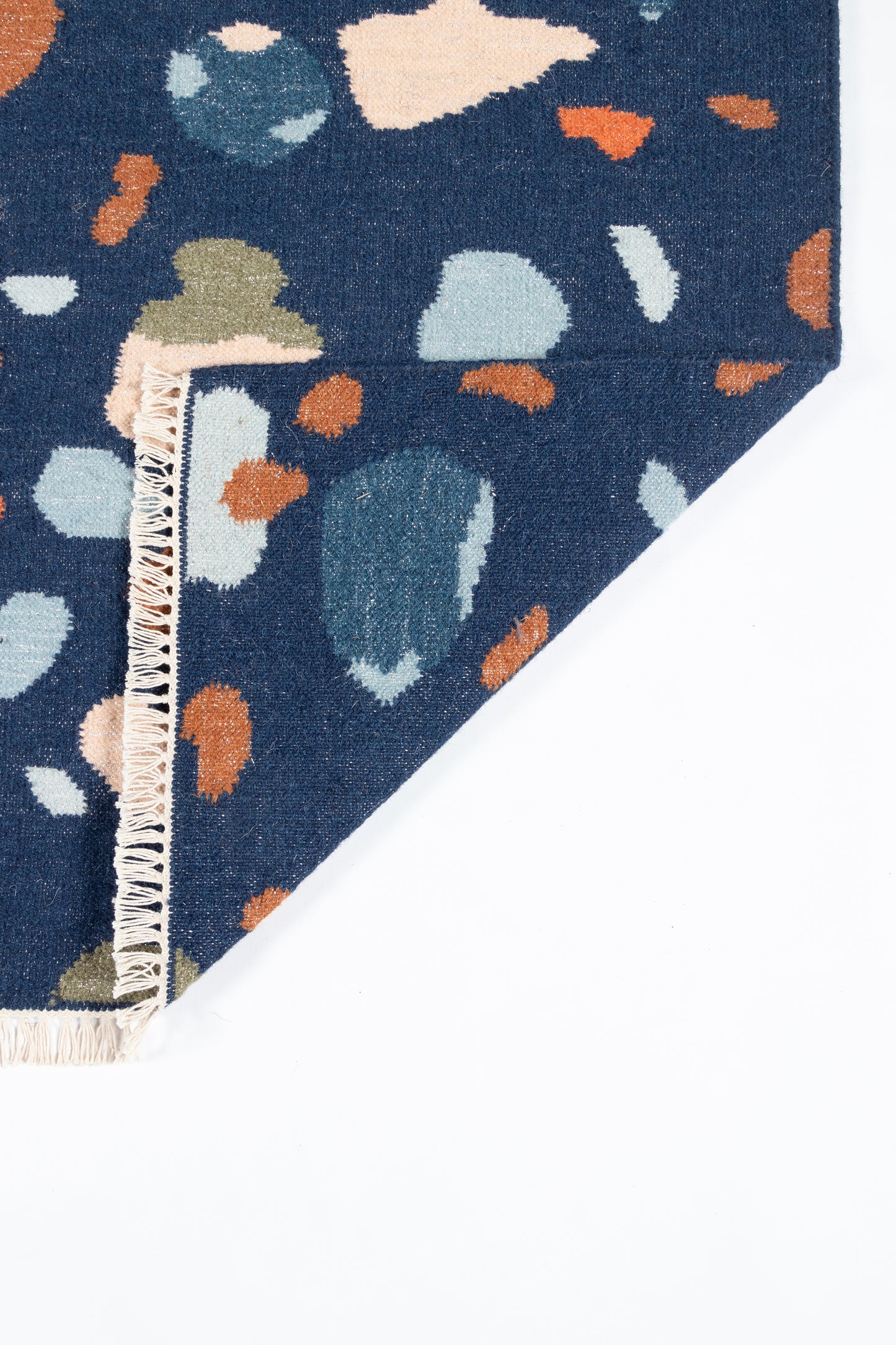 Navy blue rug with terrazzo-like multicolor blotches and a cream fringe along the edge.