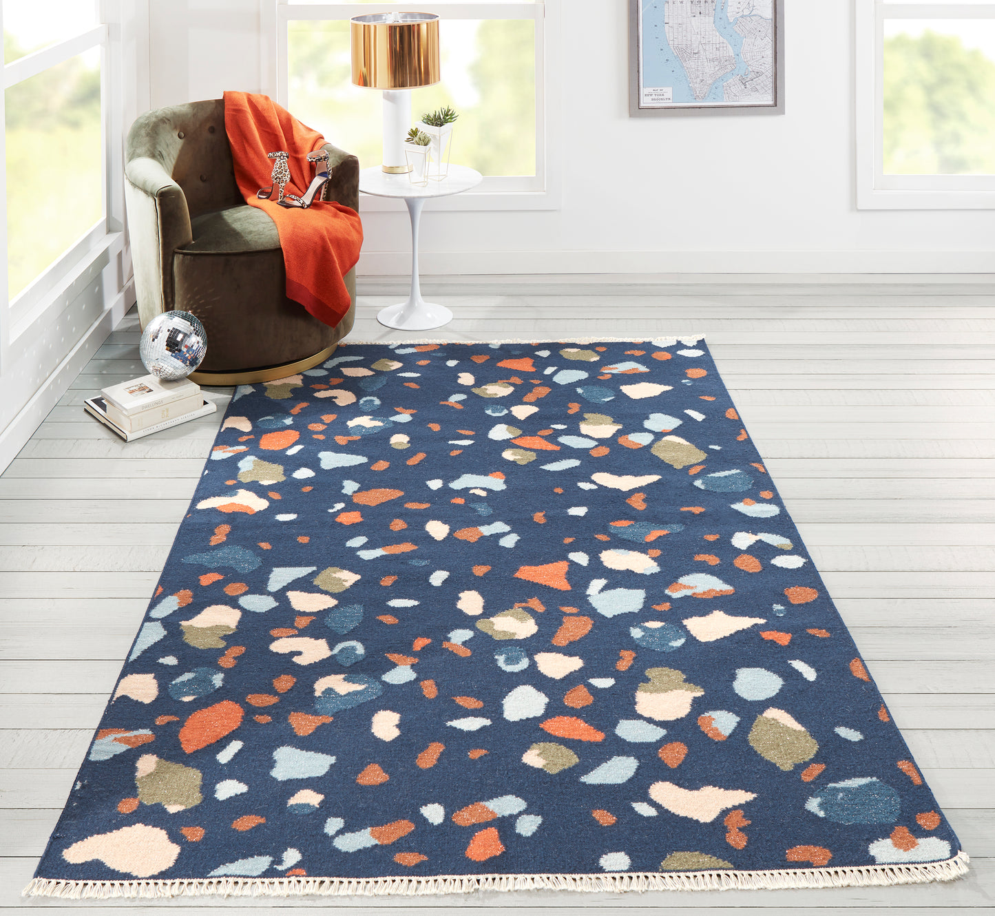 Rectangular navy blue runner rug with multicolored irregular terrazzo chips in orange, white & tan; modern living room.