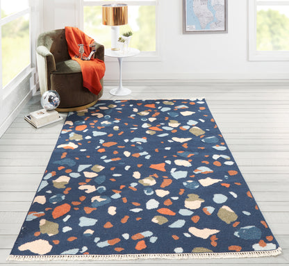 Rectangular navy blue runner rug with multicolored irregular terrazzo chips in orange, white & tan; modern living room.