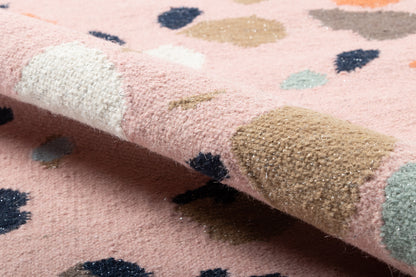Soft pink shag runner with multicolored abstract dots in navy, beige, blue, mint; curled edge visible.