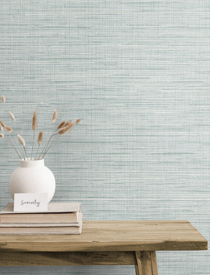 Blue rustic matte stringcloth textile on a wooden table with stacked books and a serenity card against a blue textured wall.