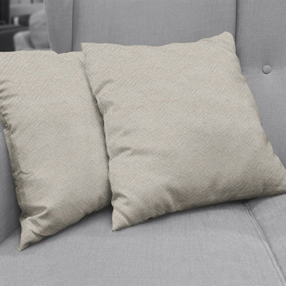 Two beige textured throw pillows on a light gray fabric sofa.