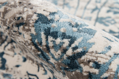 Blue and cream patterned rug close-up, plush woven pile with abstract floral motif.