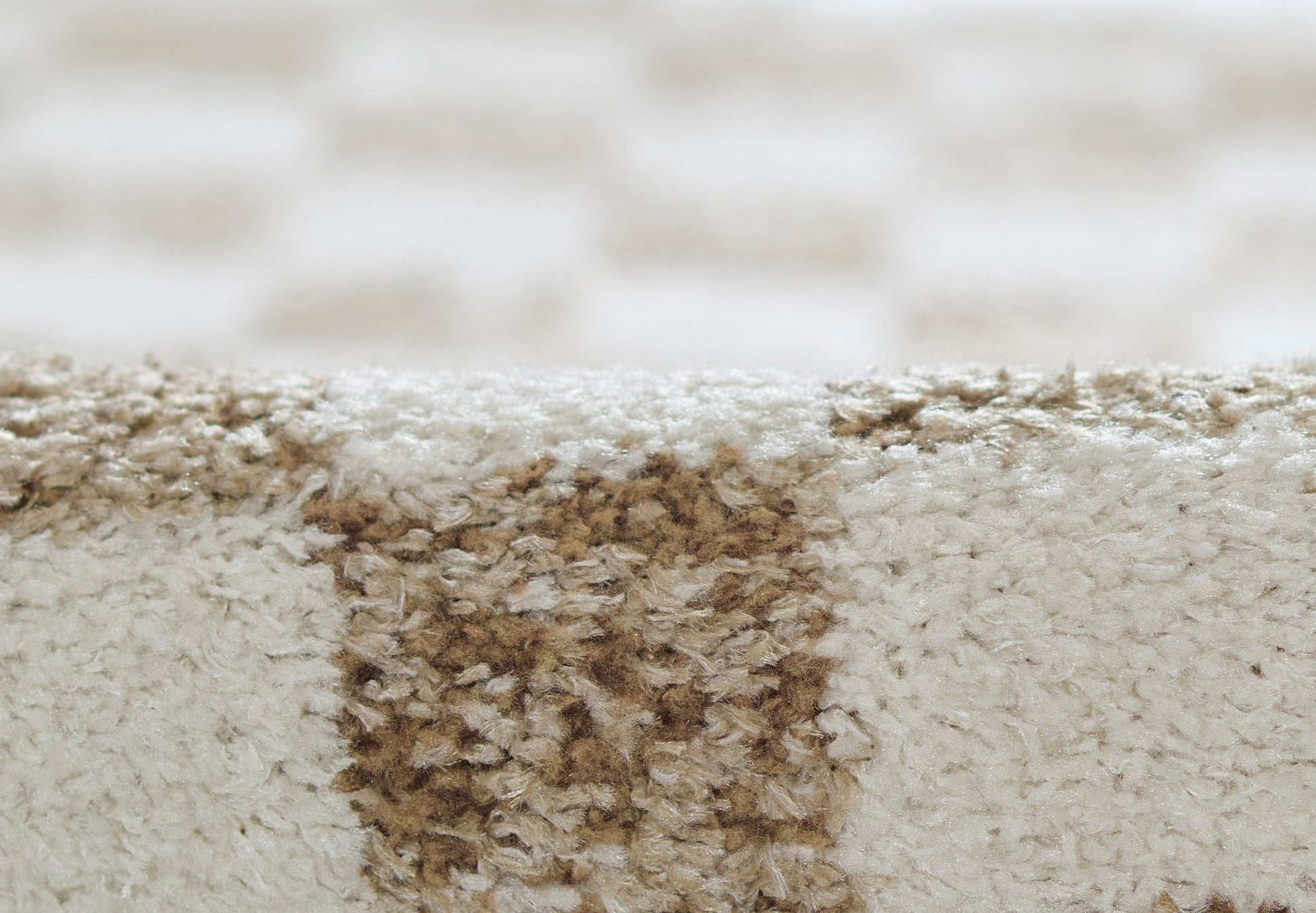 Beige plush rug with a brown stain patch and soft textured fibers for indoor flooring.