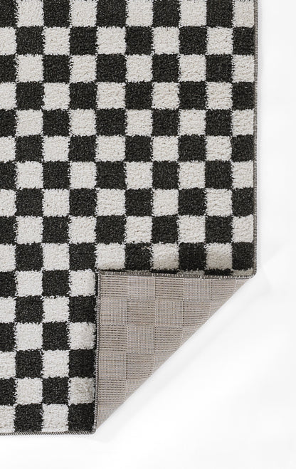 Black and white checkerboard rug with a woven texture; corner folded to reveal a gray grid-printed underside.