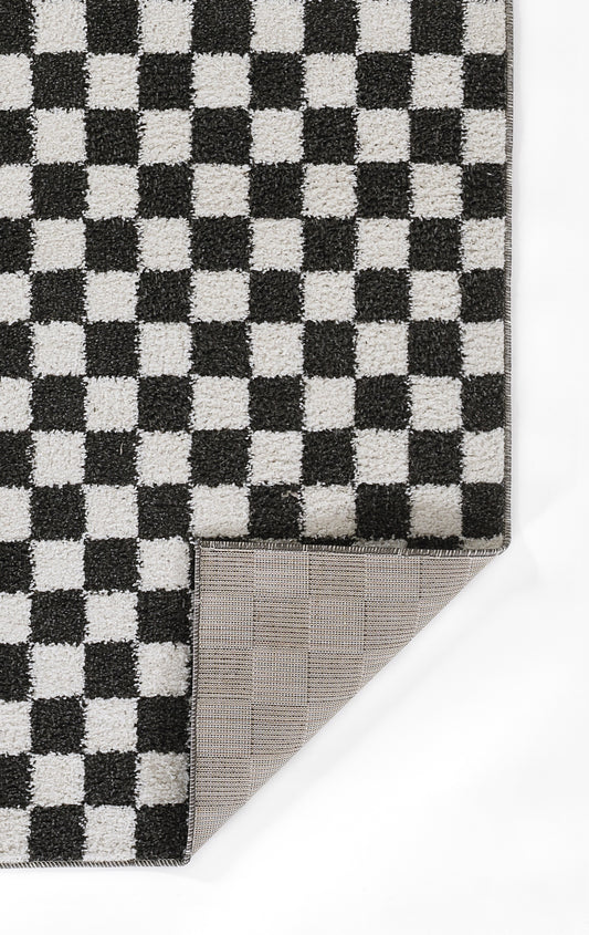Black and white checkered plush rug with thick pile; folded corner reveals beige grid-pattern underside.