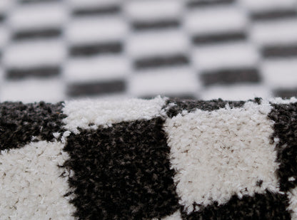 Close-up of a black-and-white checkered fuzzy rug with a soft pile.
