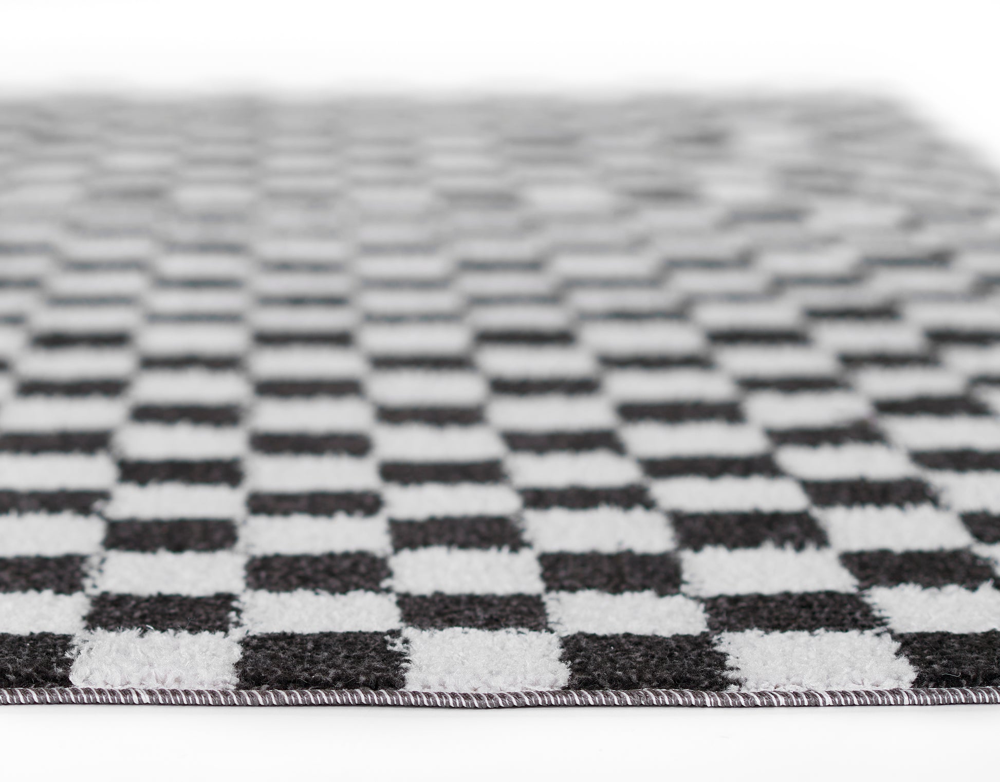 Close-up of a black & white checkerboard rug with flat weave, textured squares & a bordered edge.