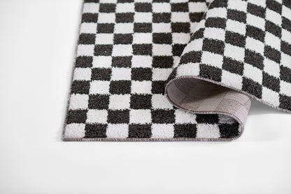 Black and white checkerboard throw blanket with soft woven texture and rolled corner.