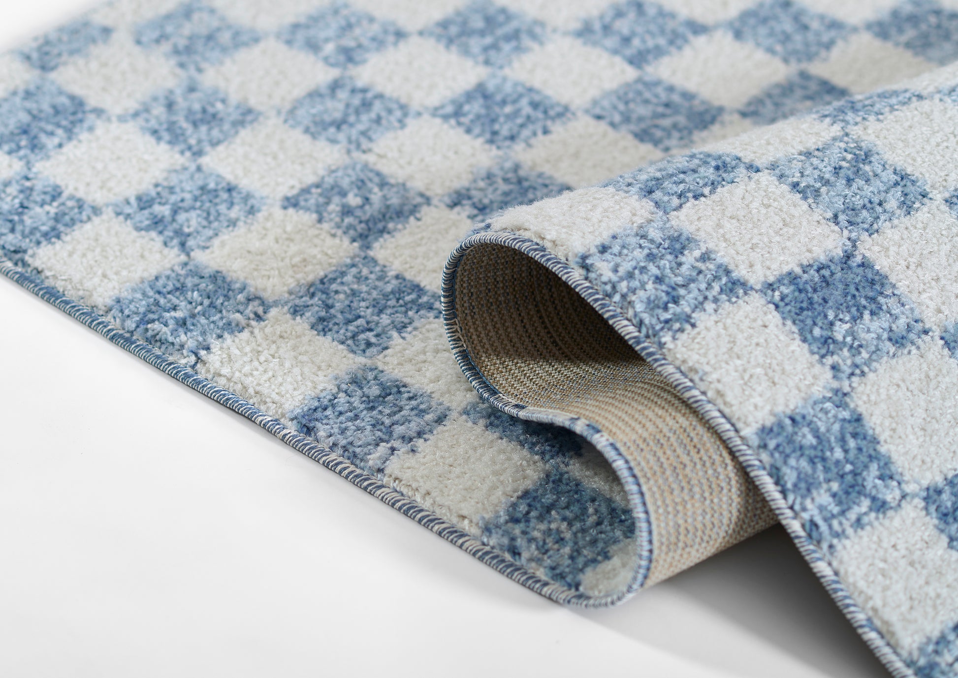 Blue and white checkered woven rug with a rolled edge, beige backing visible.