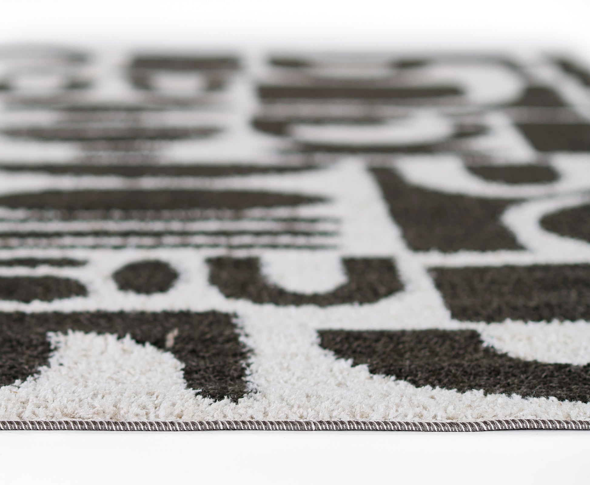 Close-up of a black and white geometric rug with a short pile and bound edge.
