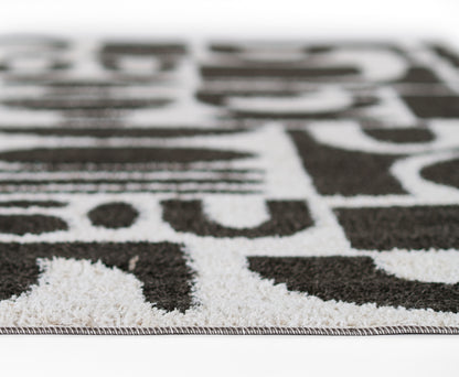Close-up of a black and white geometric rug with a short pile and bound edge.