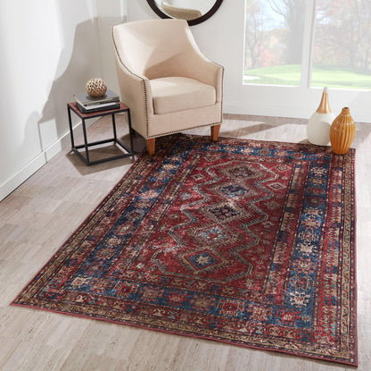 Oriental wool area rug with red, blue and ivory geometric pattern; beige armchair and side table on a light wood floor.