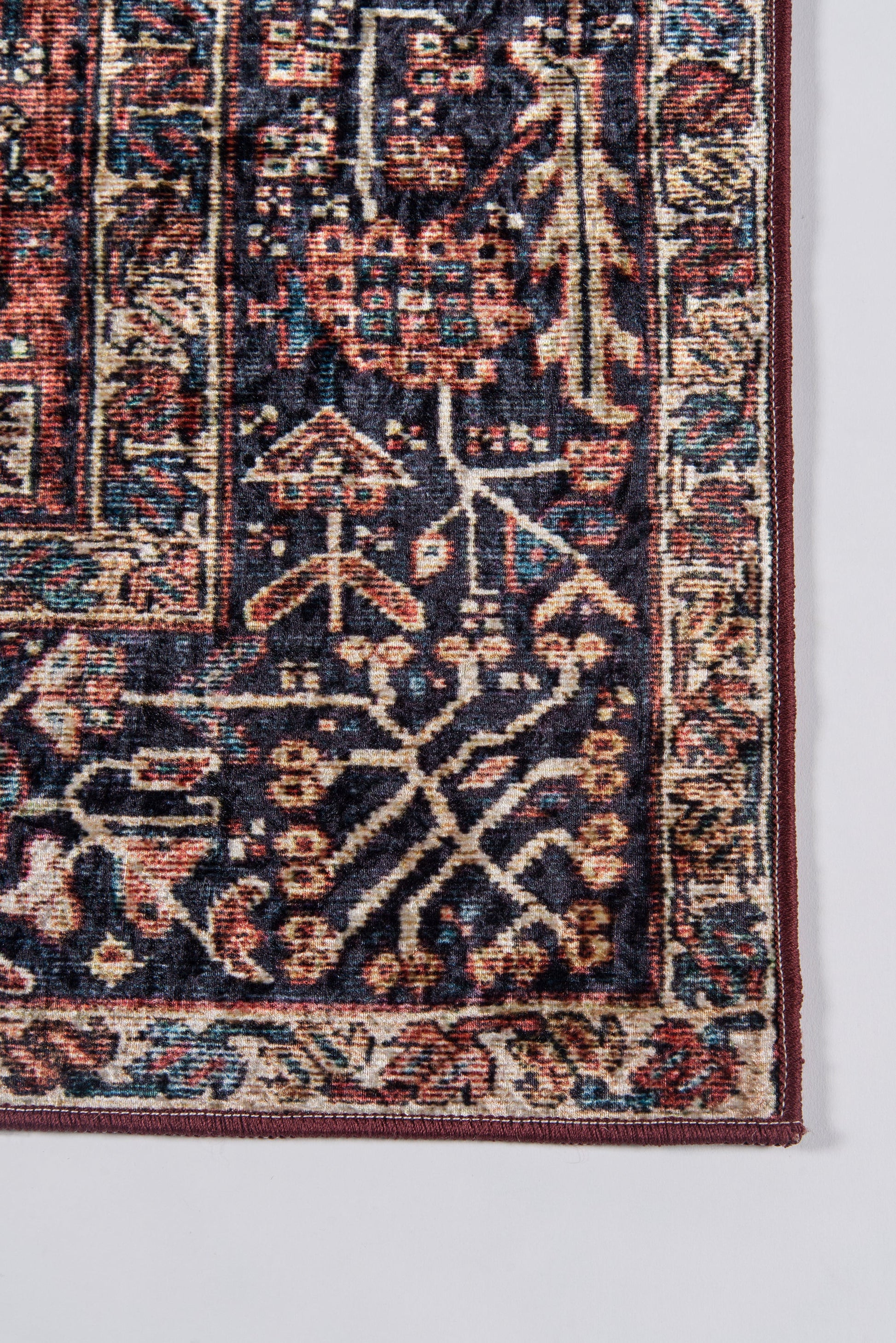 Close-up of a navy Persian-style area rug with red and ivory floral motifs and a detailed border.
