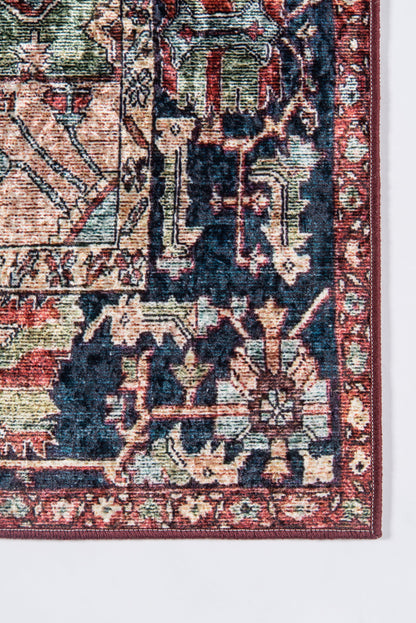 Close-up of a Persian-style woven rug corner in red, navy, and cream with a floral border.