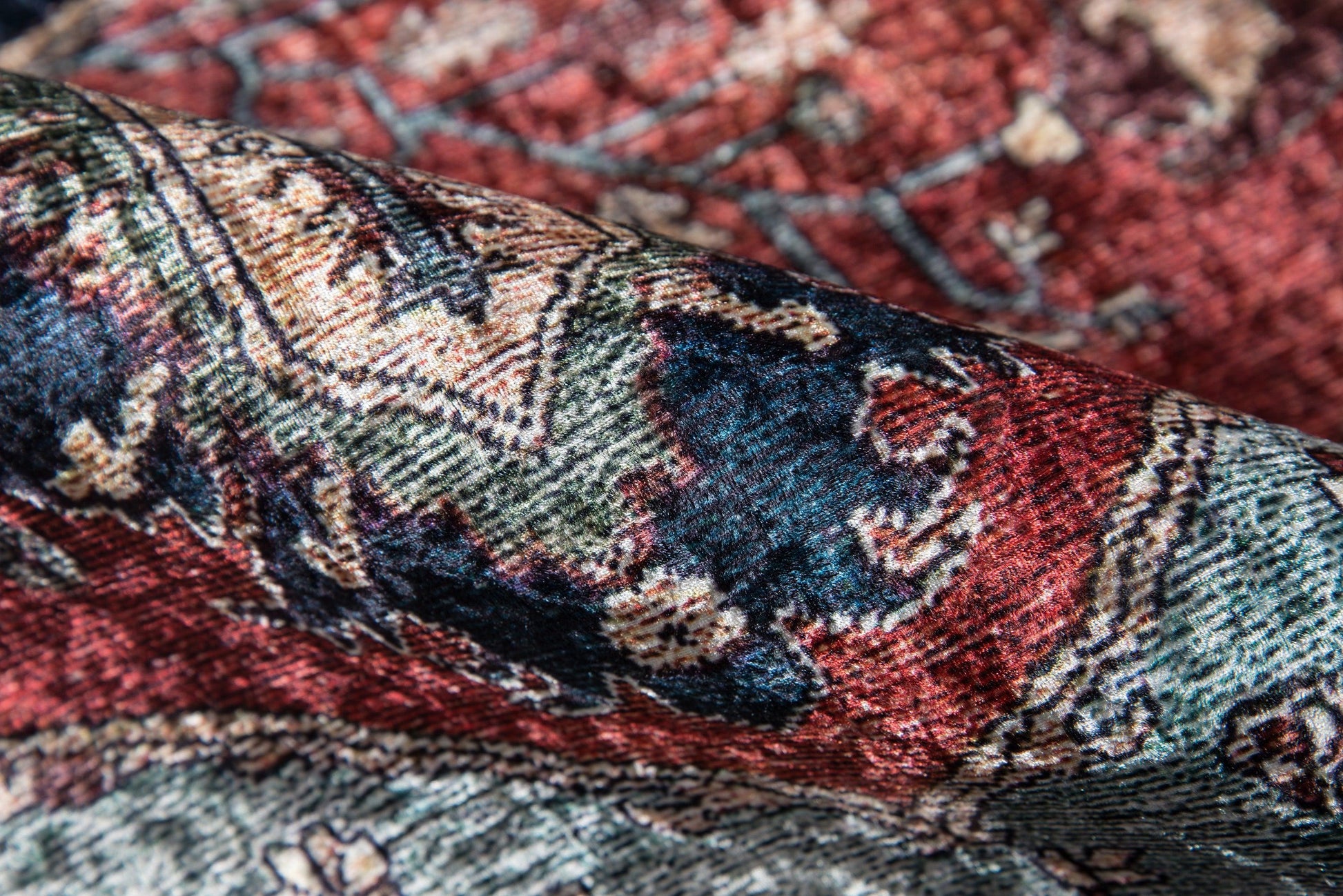Close-up of a folded oriental rug with red, blue, green and beige colors in a wool weave for home decor.